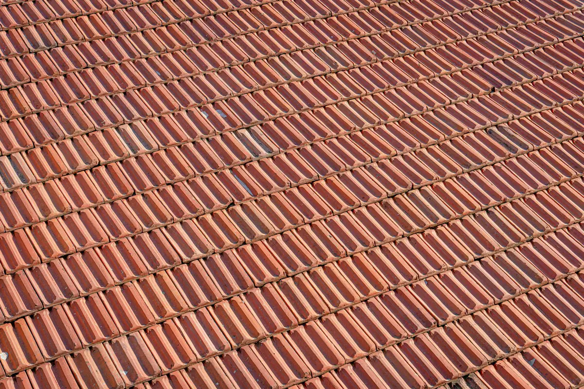 Aerial view of a textured red clay tile roof with a repeating pattern.
