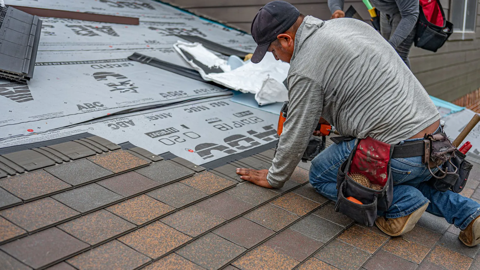 Skilled roofer installing asphalt shingles, ensuring quality home renovation.
